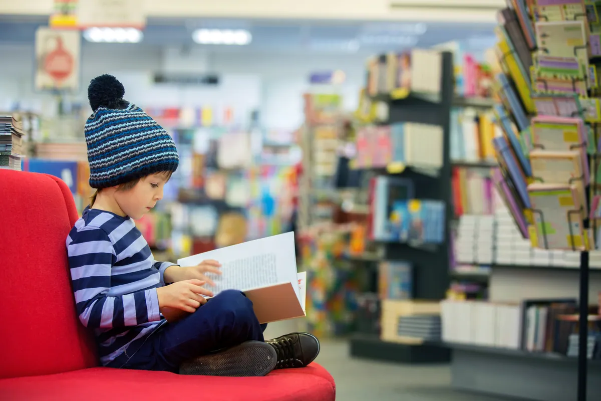 A child in a beanie hat holding a book