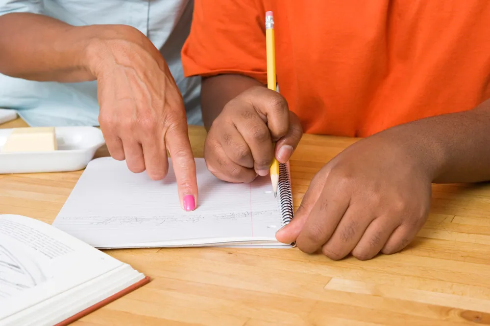 A child being helped to write by an adult