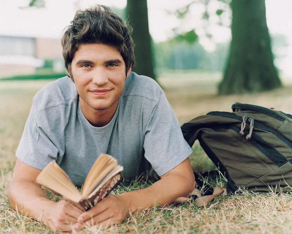 A child resting on the grass, reading a book in the sunshine
